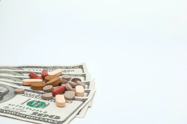 Pílulas medicinais coloridas e dólares americanos em branco um backgrou — Fotografia de Stock