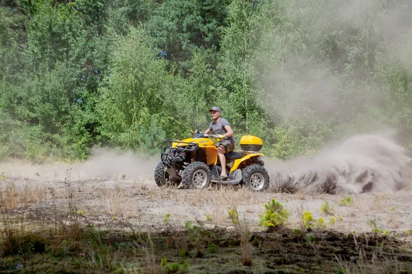 Чоловік їде на жовтому квадроциклі ATV весь рельєфний транспортний засіб на піщаному передньому плані — стокове фото