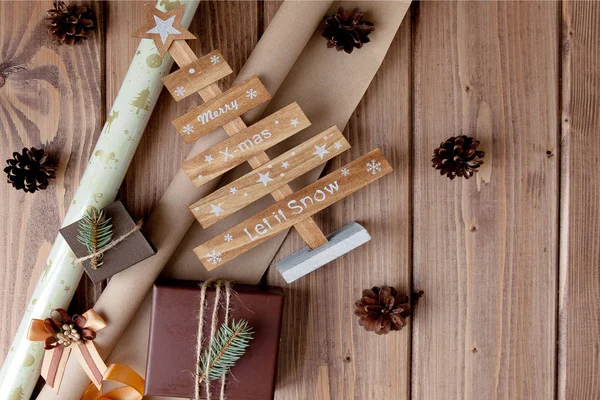 Cadeaux de Noël enveloppés dans du papier artisanal sur une table en bois. Processus — Photo