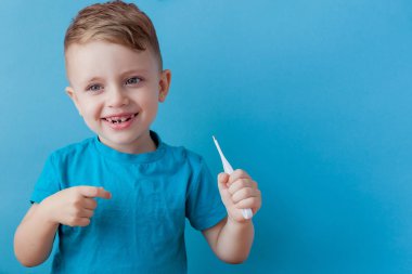 Termometresi olan hasta bir çocuk ateşinin yüksekliğini ölçüyor ve kameraya bakıyor.