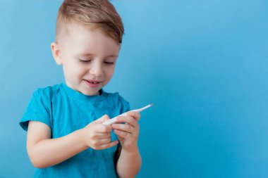 Termometresi olan hasta bir çocuk ateşinin yüksekliğini ölçüyor ve kameraya bakıyor.