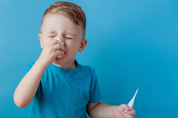 Malo niño pequeño con un termómetro, midiendo la altura de su fiebre y mirando a la cámara —  Fotos de Stock