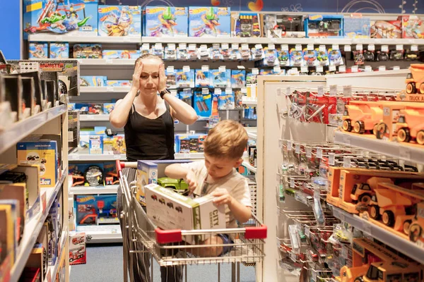 KYIV- JAN 6, 2019 : Mère avec son petit fils dans un magasin pour enfants acheter des voitures . — Photo