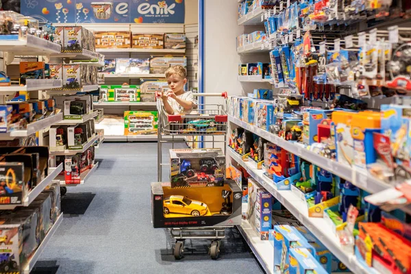 Kiev- 6 Ocak 2019: Küçük oğluyla birlikte çocuk mağazasında araba satın alan anne.