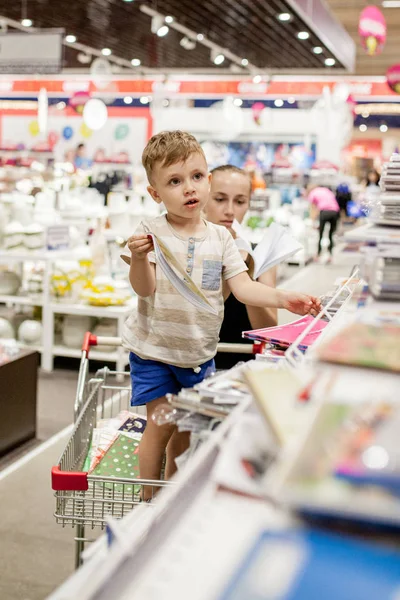 KYIV- JAN 6, 2019 : Petit garçon choisissant des fournitures scolaires avec sa mère dans un magasin de papeterie — Photo