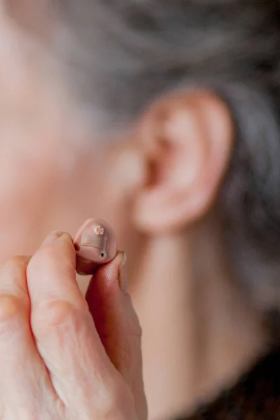 Senior vrouw close-up gehoorapparaat in haar oren invoegen — Stockfoto