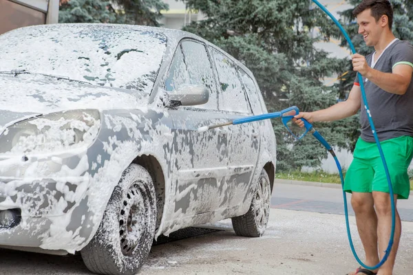 Bir adam yaz açık havada self servis lavaboda arabasını yıkar