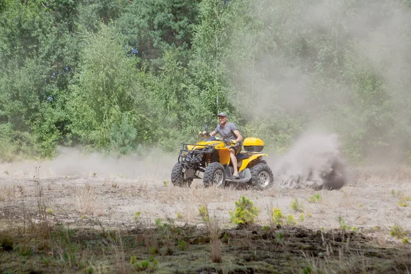 Hombre montando un quad amarillo todo terreno vehículo todo terreno en un bosque de arena. Movimiento deportivo extremo, aventura, atracción turística . —  Fotos de Stock