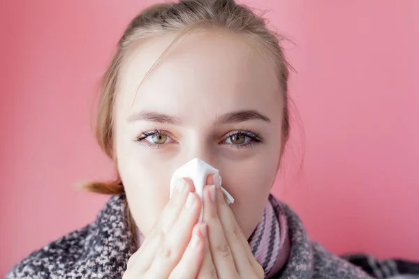 Portrait horizontal jeune fille avec un mouchoir et le nez qui coule de profil, éternuant de grippe, modèle féminin à peau blanche au mur rose. Soins de santé et concept médical . Photo De Stock