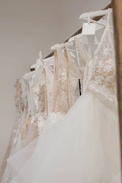 Variedade de vestidos pendurados em um cabide no estúdio de fundo. Tendências de casamento moda. Interior da loja de casamento — Fotografia de Stock