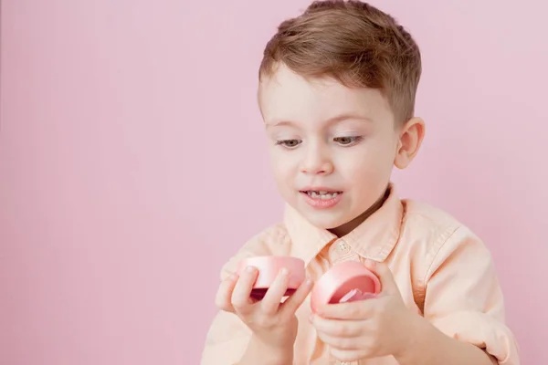 Um rapazinho feliz com um dom. Foto isolada em fundo rosa — Fotografia de Stock