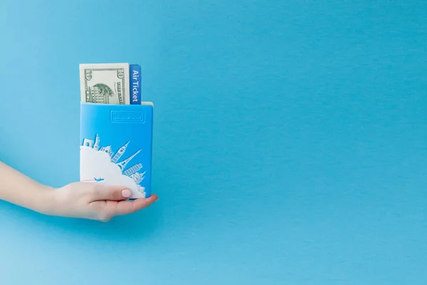 Passaporte, dólares e bilhete de avião na mão mulher em um backgro azul — Fotografia de Stock