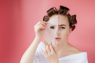 Yüzüne dokunmadan bir maske ve curlers ile güzel genç kız.