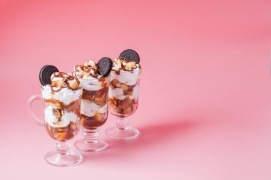 Pembe bsckground, seçici odak ve boş alan üzerinde bisküvi ve krem şanti ile cam tatlı tatlı