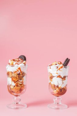 Pembe bsckground, seçici odak ve boş alan üzerinde bisküvi ve krem şanti ile cam tatlı tatlı