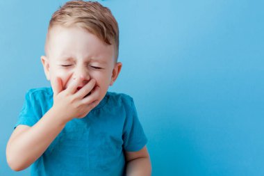 Termometresi olan hasta bir çocuk ateşinin yüksekliğini ölçüyor ve kameraya bakıyor.