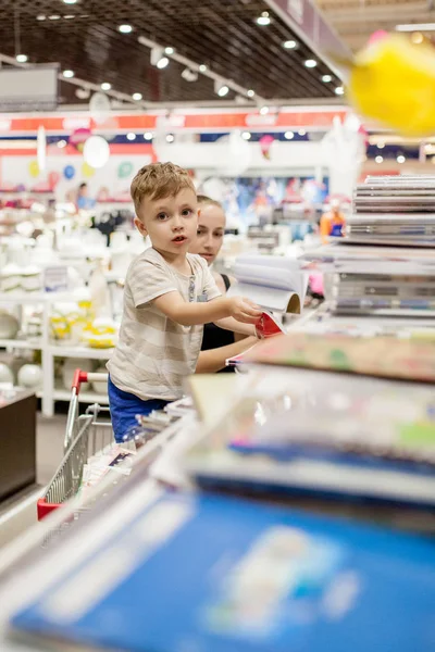 Little boy choosing school supplies with mother in stationery shop