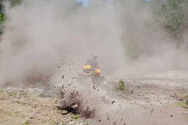 Man riding a yellow quad ATV all terrain vehicle on a sandy forest. Extreme sport motion, adventure, tourist attraction.