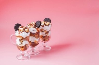 Pembe bsckground, seçici odak ve boş alan üzerinde bisküvi ve krem şanti ile cam tatlı tatlı