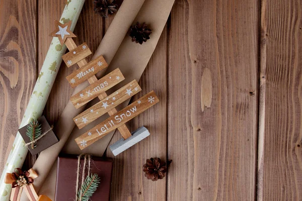 Cadeaux de Noël enveloppés dans du papier artisanal sur une table en bois. Processus d'emballage des cadeaux. Mode de vie. Vue d'en haut. Concept de Noël — Photo