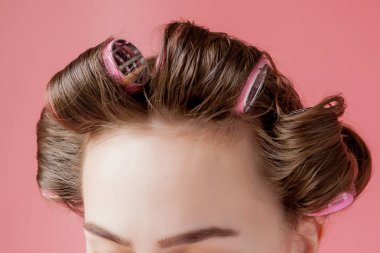 Pembe arka planda saç bigudili güzel bir kız.