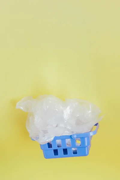 Polythene bags in shopping basket on yellow background — Stock Photo, Image