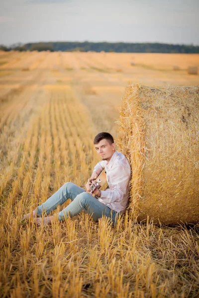 Ung kille är avkopplande på landsbygden med en gitarr. Spelar th — Stockfoto