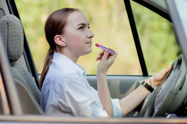 Фотографія молодої бізнес-леді, яка робить макіяж під час водіння автомобіля в пробці — стокове фото