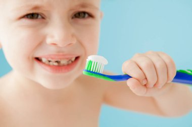 Mavi arka planda diş fırçası olan küçük bir çocuğun portresi