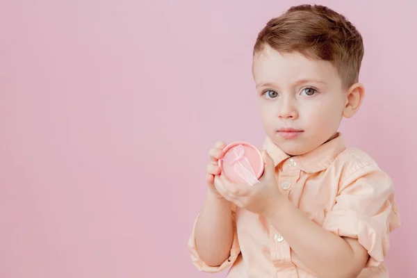 Gelukkig jongetje met een cadeau. Foto geïsoleerd op roze achtergrond — Stockfoto