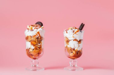 Pembe bsckground, seçici odak ve boş alan üzerinde bisküvi ve krem şanti ile cam tatlı tatlı