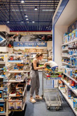 Kiev- 6 Ocak 2019: Küçük oğluyla birlikte çocuk mağazasında araba satın alan anne.