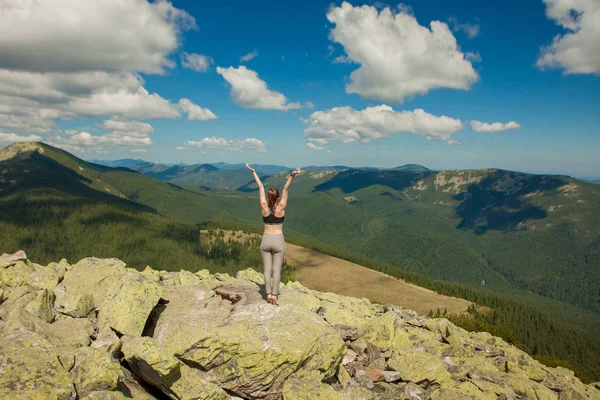 La ragazza in cima alla montagna alzò le mani. Ampia vista sulle montagne estive all'alba e catene montuose lontane coperte. Bellezza della natura concetto — Foto Stock