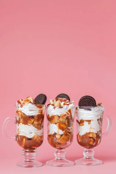 Sweet dessert in glass with biscuit and whipped cream on pink bsckground, selective focus and blank space — Stock Photo, Image