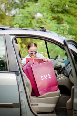 Araba alışveriş kavramı içine onu alışveriş torbaları ile kadın.