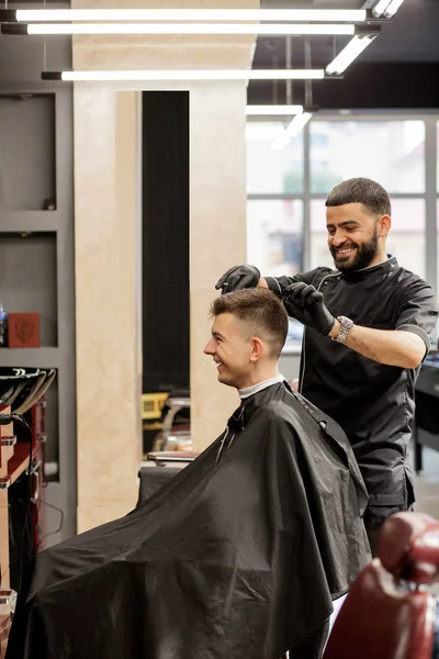 Brutal guy in modern Barber Shop. Hairdresser makes hairstyle a — Stock Photo, Image