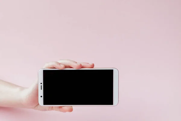 Moderní mobilní telefon v ženské ruce na růžovém pozadí — Stock fotografie