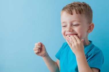 Little Boy Holding ve mavi arka plan, gıda, diyet ve sağlıklı beslenme kavramı bir Muz yeme