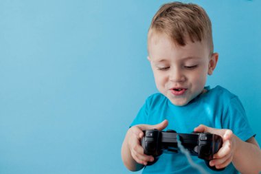 Küçük çocuk çocuk 2-3 yaşında mavi giysiler giyen gameson mavi arka plan çocuk stüdyo portre için el joystick tutun. İnsanlar çocukluk yaşam tarzı kavramı. Kopya alanı yla alay edin