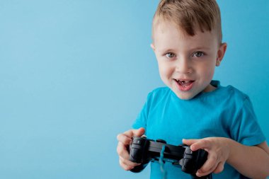 Küçük çocuk çocuk 2-3 yaşında mavi giysiler giyen gameson mavi arka plan çocuk stüdyo portre için el joystick tutun. İnsanlar çocukluk yaşam tarzı kavramı. Kopya alanı yla alay edin