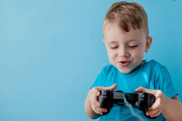 Bambino bambino 2-3 anni indossa vestiti blu tenere in mano joystick per giochisu sfondo blu bambini studio ritratto. Persone concetto di stile di vita infantile. Falsificare spazio di copia — Foto Stock