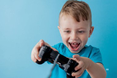 Küçük çocuk çocuk 2-3 yaşında mavi giysiler giyen gameson mavi arka plan çocuk stüdyo portre için el joystick tutun. İnsanlar çocukluk yaşam tarzı kavramı. Kopya alanı yla alay edin