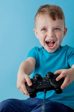 Küçük çocuk çocuk 2-3 yaşında mavi giysiler giyen gameson mavi arka plan çocuk stüdyo portre için el joystick tutun. İnsanlar çocukluk yaşam tarzı kavramı. Kopya alanı yla alay edin