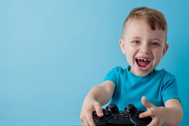 Küçük çocuk çocuk 2-3 yaşında mavi giysiler giyen gameson mavi arka plan çocuk stüdyo portre için el joystick tutun. İnsanlar çocukluk yaşam tarzı kavramı. Kopya alanı yla alay edin
