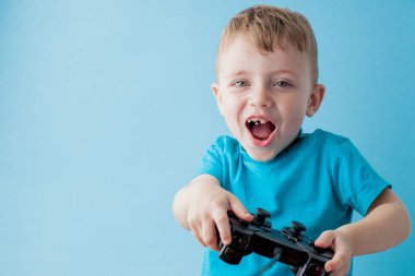 Küçük çocuk çocuk 2-3 yaşında mavi giysiler giyen gameson mavi arka plan çocuk stüdyo portre için el joystick tutun. İnsanlar çocukluk yaşam tarzı kavramı. Kopya alanı yla alay edin