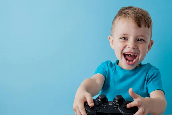 Bambino bambino 2-3 anni indossa vestiti blu tenere in mano joystick per giochisu sfondo blu bambini studio ritratto. Persone concetto di stile di vita infantile. Falsificare spazio di copia — Foto Stock