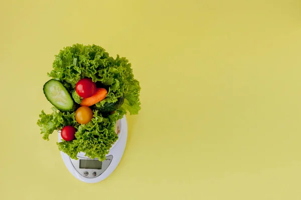 Fresh vegetables on scales on yellow background. Vegan and healt