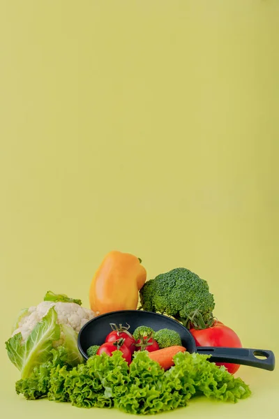 Verse groenten op koekepan op gele achtergrond. Veganistisch en gezond concept — Stockfoto