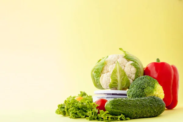 Свіжі овочі на вазі на жовтому тлі. Здорове харчування, планування дієти, втрата ваги, детоксикація, концепція органічного землеробства — стокове фото