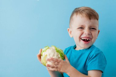 Küçük Çocuk mavi arka plan üzerinde elinde Brokoli Holding, ölmek